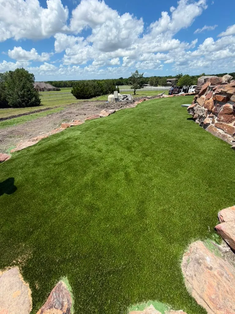Artificial turf installation integrated into a sloped rock landscape