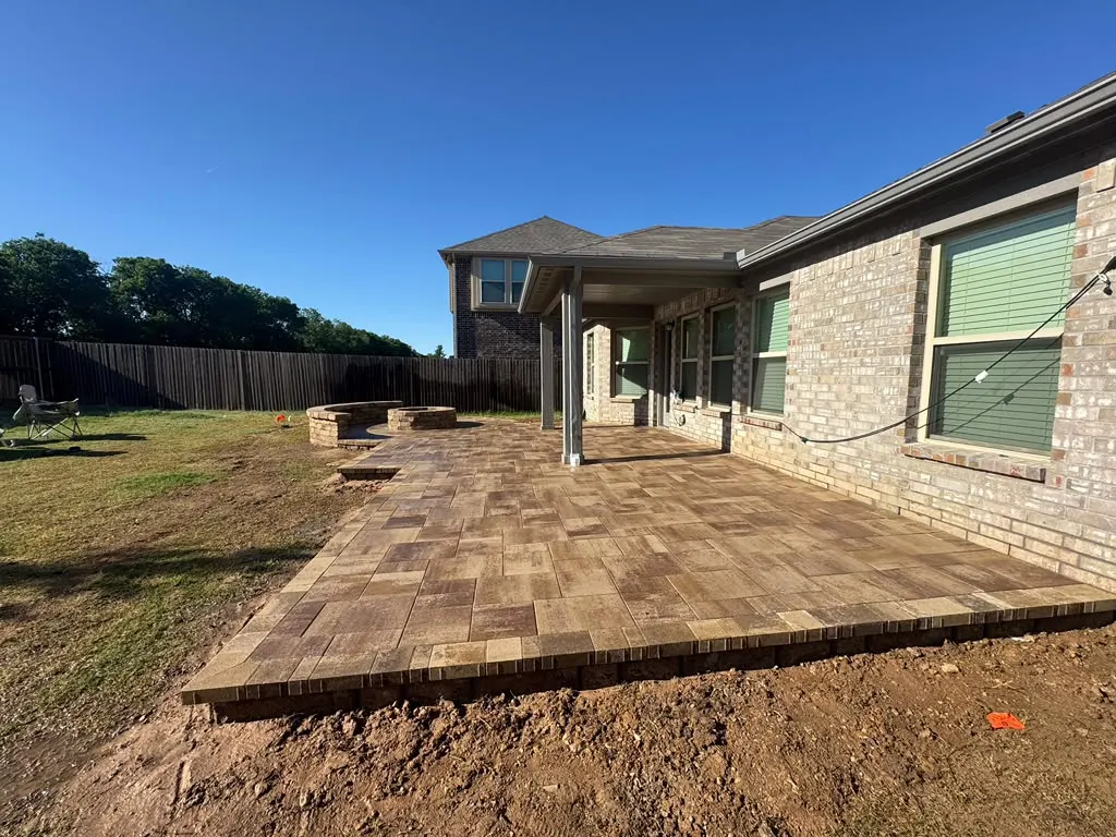 Large brown paver patio extending from a covered back porch