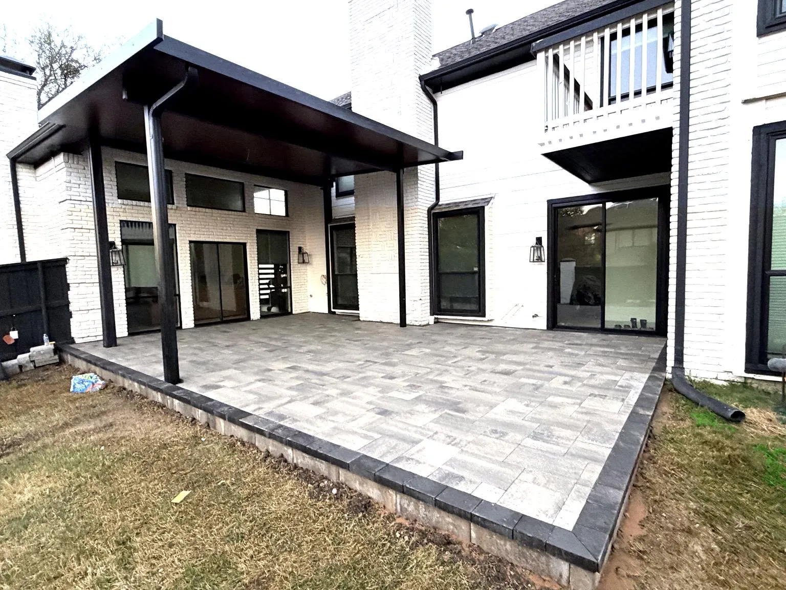 Covered patio with gray pavers and black structural posts