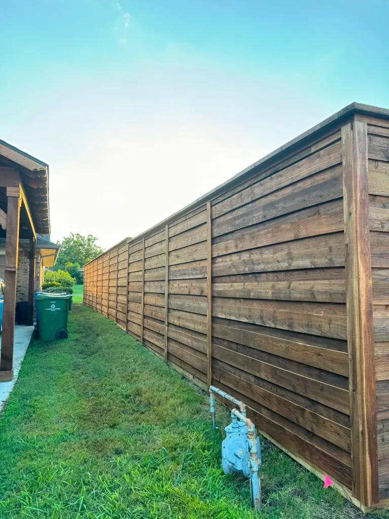 Horizontal stained wood privacy fence along a side yard