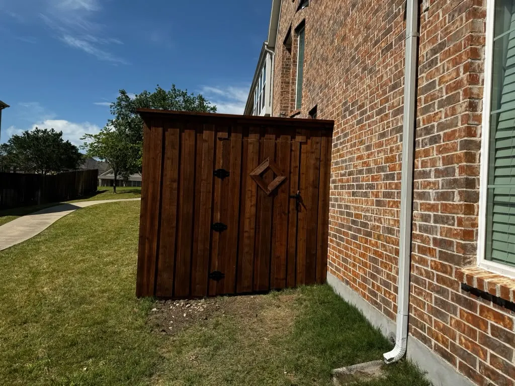 Stained wood utility enclosure built against a brick home