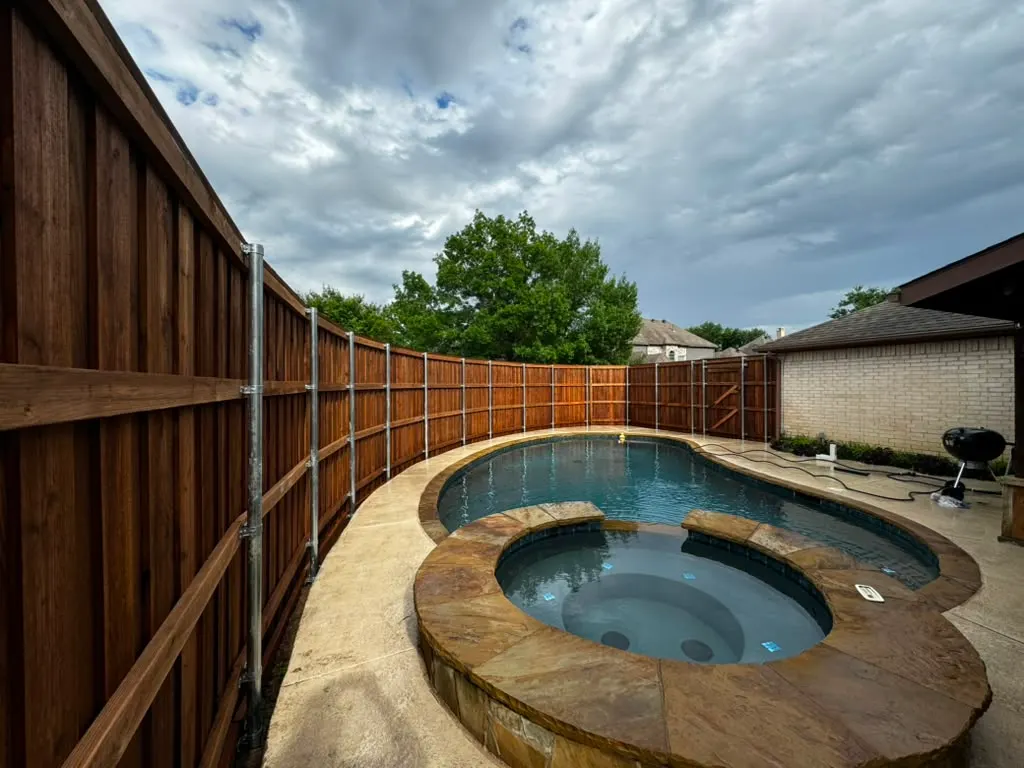 Stained wood privacy fence surrounding a pool and spa