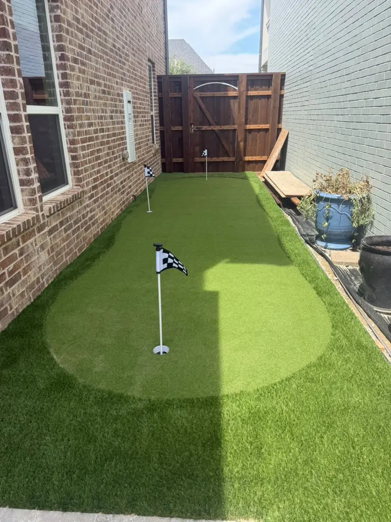 Compact artificial turf putting green installed between two homes